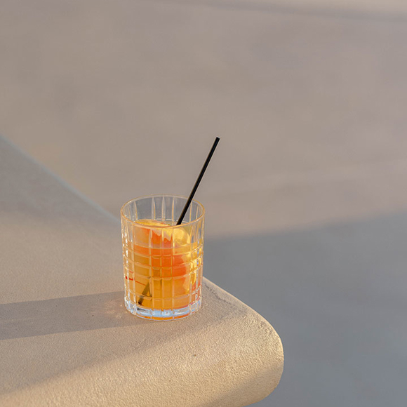 Grand Ambassador pool bar orange cocktail with straw on poolside edge
