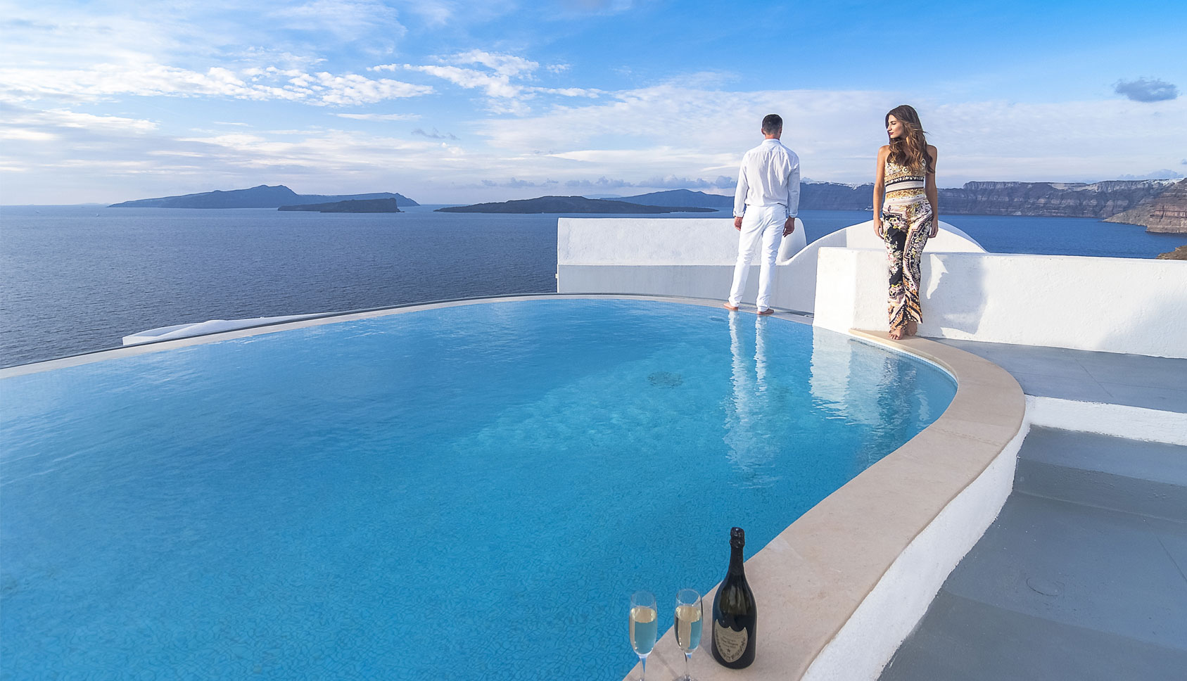 Man and woman by infinity pool overlooking Aegean Sea and islands from Grand Ambassador