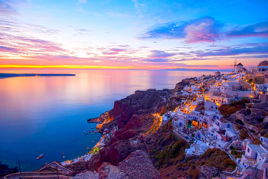 Santorini clifftop village glowing at sunset with colorful sky and sea views
