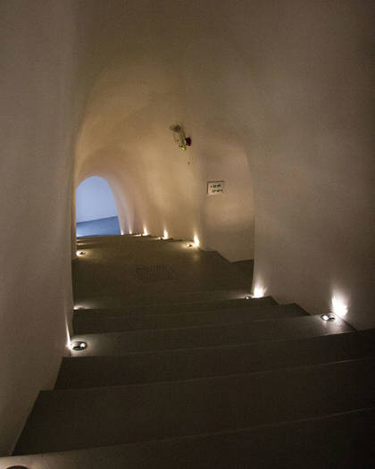 Dimly lit curved staircase with small recessed lights at Grand Ambassador Hotel