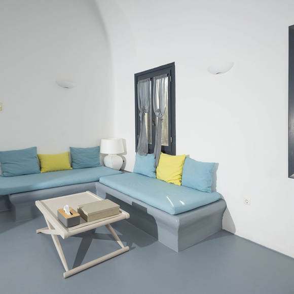 Grand Ambassador Santorini Serenity Two Bedroom Suite living room with corner built-in blue sofas, yellow accent pillows, and minimalist design