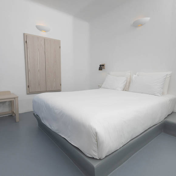 Grand Ambassador Santorini Serenity Two Bedroom Suite minimalist bedroom with double bed, wood accents, and Cycladic design
