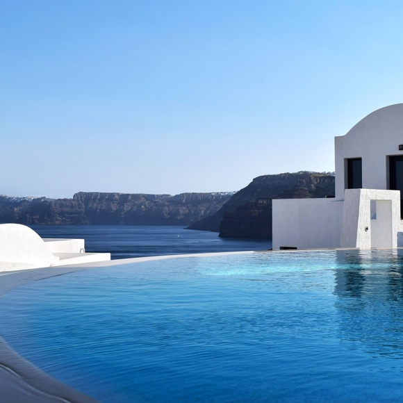 Infinity pool overlooking the sea and volcanic cliffs at Grand Ambassador hotel, with whitewashed buildings under a clear blue sky