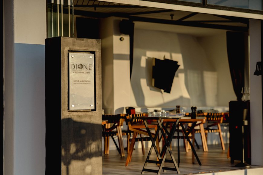 Grand Ambassador Dione restaurant entrance with Mediterranean cuisine sign and modern dining tables