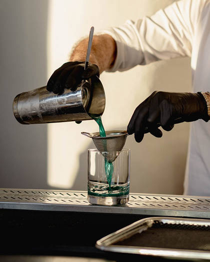 Grand Ambassador pool bar bartender straining and pouring blue cocktail into glass