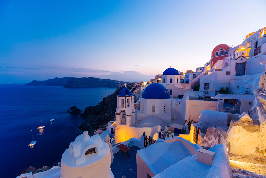 Santorini view of blue-domed churches, whitewashed houses, and caldera at sunset